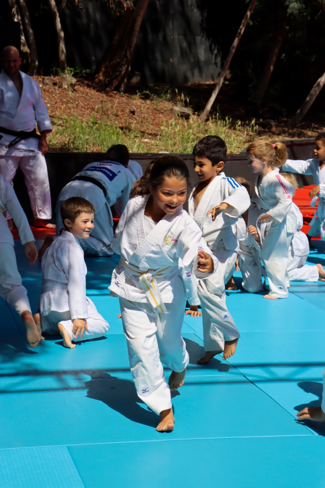 Des enfants souriants en mouvement sur le tatami lors de la fête du club